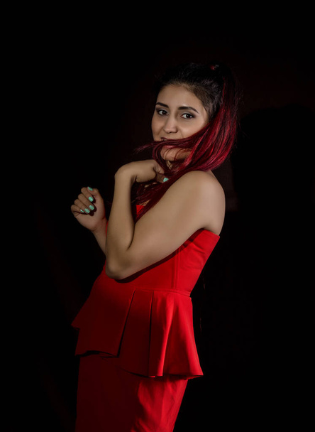 Pretty young sexy asian model with red hair in amazing red dress on dark background - Fotó, kép
