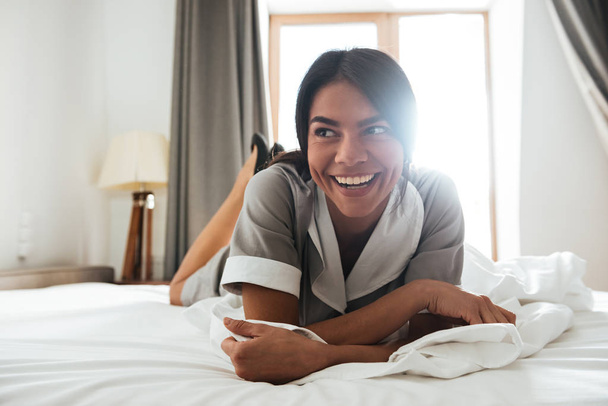 Smiling hotel maid lying on a bed - Фото, зображення