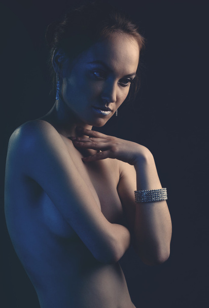 jonge naakte sexy vrouw met martini glas in blauw licht - Foto, afbeelding