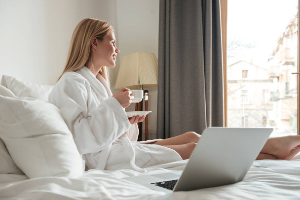 Young pretty woman in bathrobe drinking coffee - Photo, Image