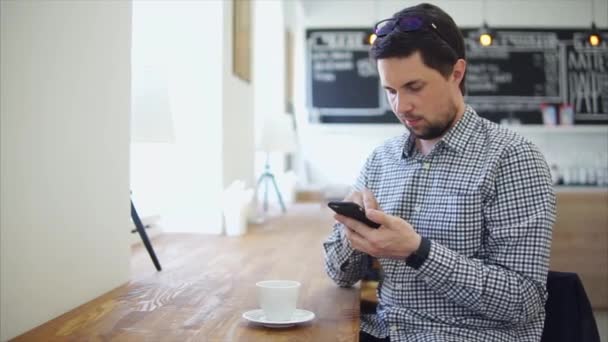 Взрослый мужчина общается по телефону сидя в кофейне
 - Кадры, видео