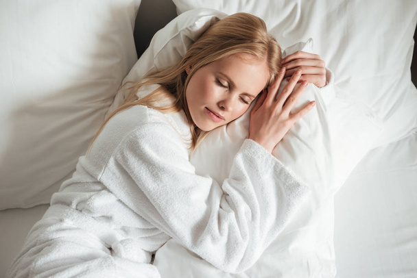 Lovely young woman in bathrobe sleeping on bed - Fotoğraf, Görsel