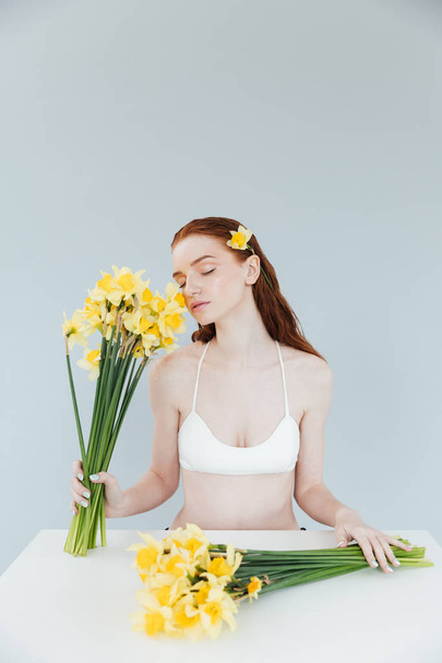 Young redheaded woman holding two bouquets of narcisuss - Photo, image