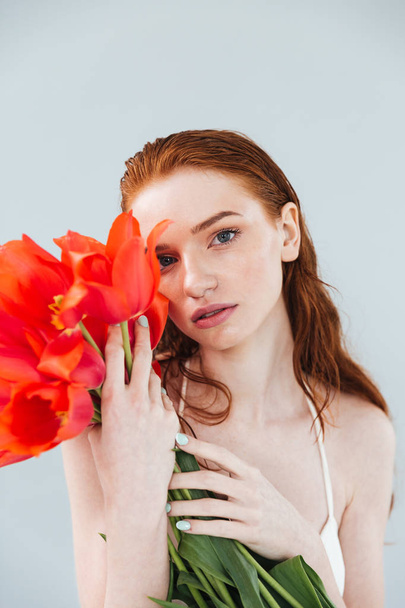Close up portrait of a redheaded woman holding tulip flowers - Foto, Imagen