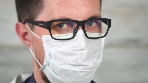 Portret van een jonge man die draagt een bril en een lap masker op zijn gezicht - Video