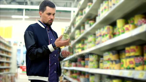 Ο άνθρωπος επιλέγοντας κονσερβοποιημένα λαχανικά στο σουπερμάρκετ - Πλάνα, βίντεο
