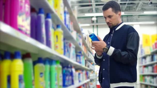 Mężczyzna w sklepie czytanie etykiet na detergent - Materiał filmowy, wideo