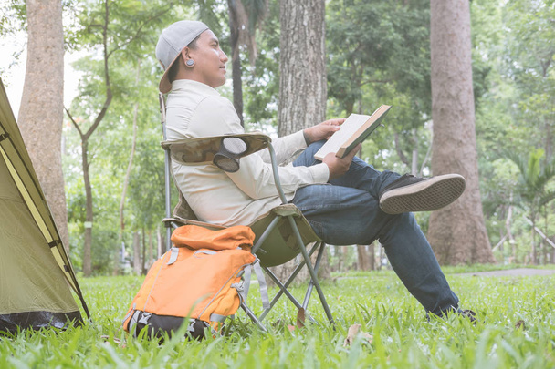 jongeman toeristische zittend op een stoel en leesboek voor  - Foto, afbeelding