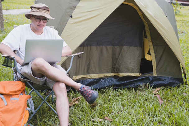 молодий чоловік турист сидить на стільці і використовує ноутбук перед
  - Фото, зображення