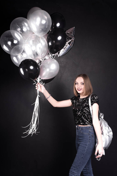 Close up fashion portrait of a young beautiful elegant girl with bright party make up in evening black sequin top. She is keeping silver stars balloons in her hand. Girl at the party. Retouched shot - Photo, Image