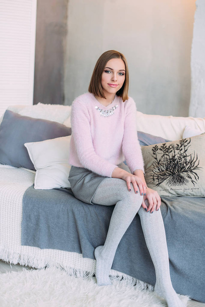 Soft photo of fresh young woman in pink tender sweater smiling. Pretty girl enjoying early sunny morning at home. - Valokuva, kuva