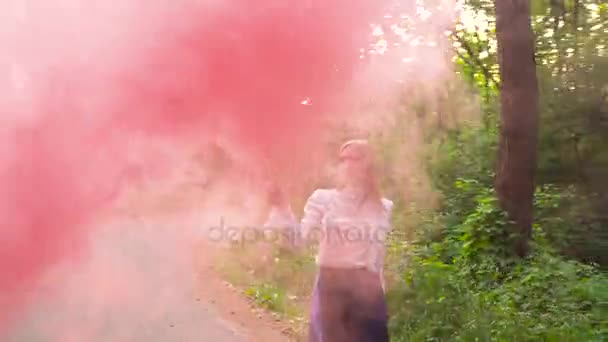 Nainen kauniissa vaatteissa kulkee metsän läpi heiluttaen värillistä savua
 - Materiaali, video
