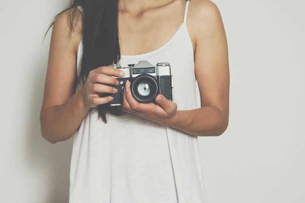 Жінка тримає старовинну камеру перед білим тлом
 - Фото, зображення
