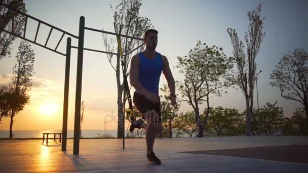 Zdrowy silny człowiek zaangażowany w trx ćwiczenia skok treningu odkryty świt slowmotion - Materiał filmowy, wideo