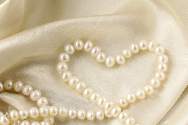 Collana di perle a forma di cuore su tessuto di seta
 - Foto, immagini