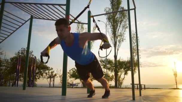 heiße starke Mann in Trax-Übungen engagiert ziehen Workout Outdoor-Dämmerung Zeitlupe - Filmmaterial, Video