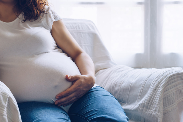 Mulher grávida bonita sentada em poltrona em casa
 - Foto, Imagem