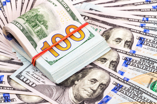 Διπλωμένο λογαριασμούς δολαρίων τυλιγμένο από λάστιχο πάνω από δολάρια τραπεζογραμματίων - Φωτογραφία, εικόνα