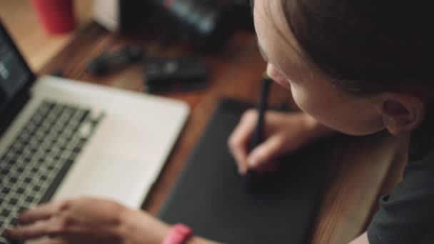 Vrouw ontwerper werkt op een laptop met een grafische tablet. - Video