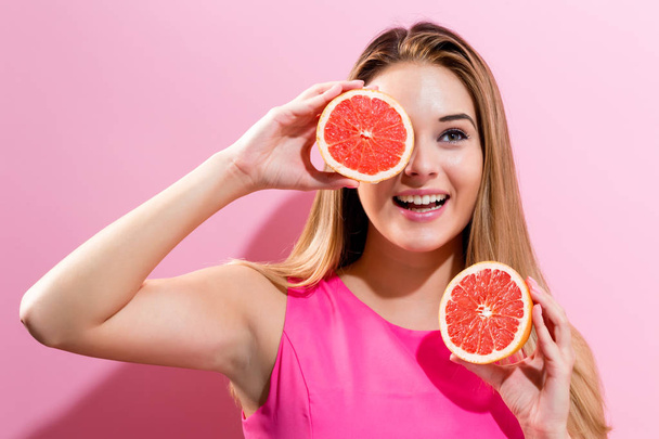 Happy young woman holding grapefruit halves - Фото, изображение