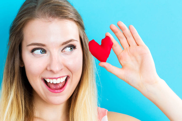 Happy young woman holding a heart cushion - 写真・画像