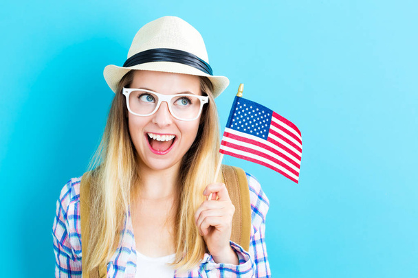 Happy young traveling woman holding American flag - Foto, imagen