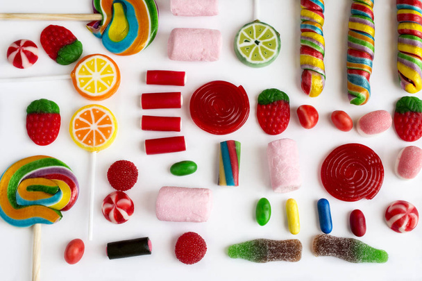 Piruletas coloridas y dulces y dulces de diferentes colores sobre fondo blanco
. - Foto, Imagen