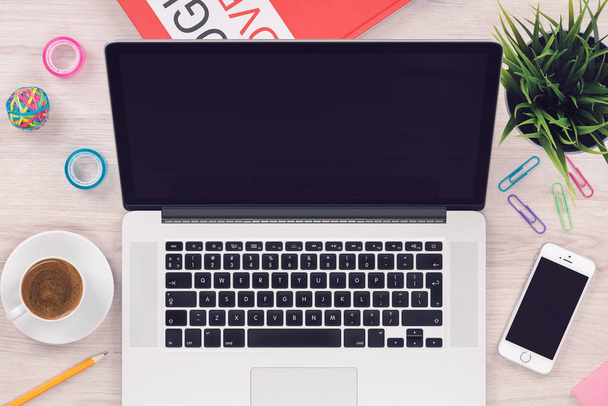Vrcholový pohled plochý položte pracovní prostor s otevřeným MacBook notebookem a iPhone smartphone na kancelářského dřevěném stole - Fotografie, Obrázek