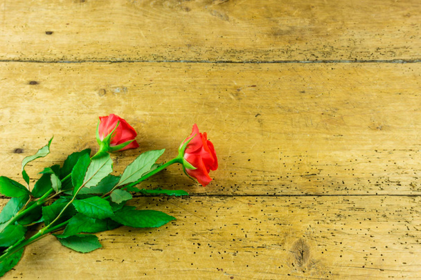 Red roses on a rustic wooden board as a background - Foto, afbeelding