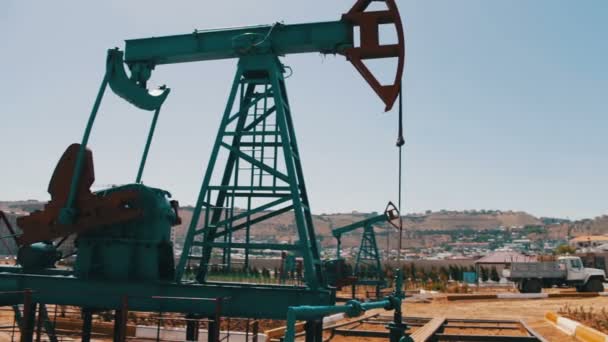 Silueta pracuje olejové čerpadlo a staré rezavé železné barel poblíž na pozadí modré oblohy a mraky. Pumpjacks ropy v práci ropné pole v Baku, Ázerbájdžán. - Záběry, video