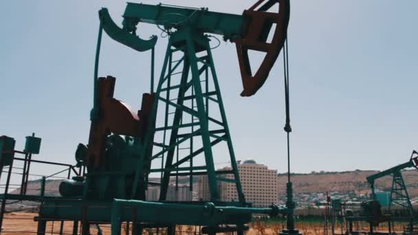 Silueta de la bomba de aceite de trabajo y un viejo barril de hierro oxidado cerca sobre un fondo de cielo azul y nublas.Petroleras en un campo petrolero de trabajo en Bakú, Azerbaiyán
. - Metraje, vídeo
