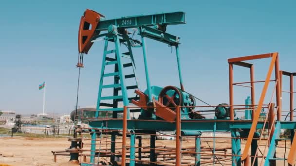 Sziluettjét olajszivattyú és egy régi rozsdás vas hordó közelében a háttér a kék ég és a felhők. Olaj pumpjacks működő olaj mezőben lévő Baku, Azerbajdzsán. - Felvétel, videó