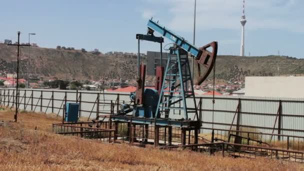 Silhueta de bomba de óleo de trabalho e um velho barril de ferro enferrujado perto de um fundo de céu azul e nuvens.Abóboras de óleo em um campo de petróleo de trabalho em Baku, Azerbaijão
. - Filmagem, Vídeo
