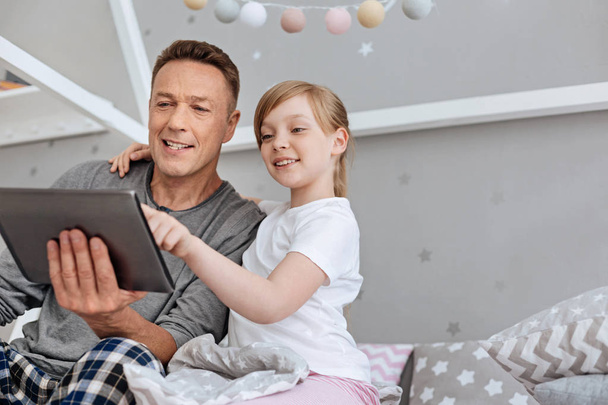 Cute engaged family watching something on tablet - Фото, изображение
