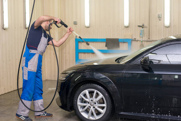 A man washes a black car with foam - Photo, image
