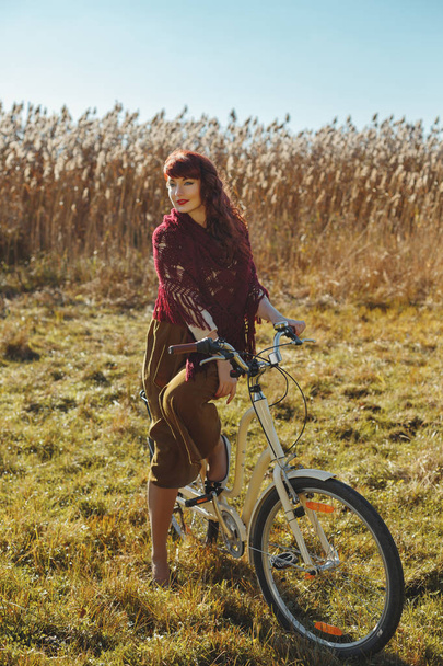Pretty girl riding bicycle in field - Фото, изображение