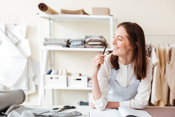 Smiling woman seamstress with pencil looking aside - Zdjęcie, obraz