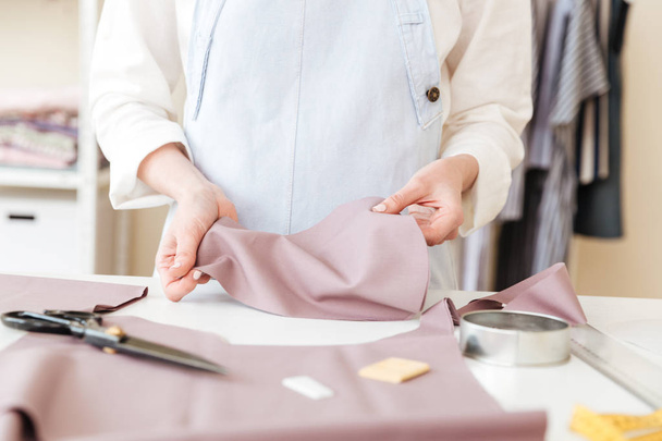Cropped image of seamstress holding piece of fabric - Zdjęcie, obraz