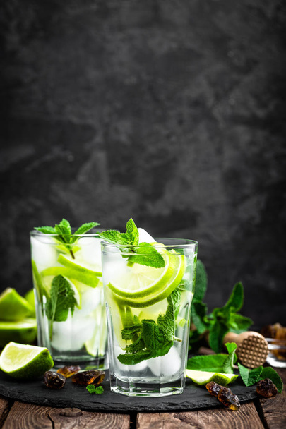 Refreshing mint cocktail mojito with rum and lime, cold drink or beverage with ice on black background - Foto, Bild