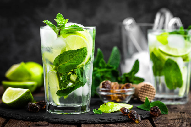 Refreshing mint cocktail mojito with rum and lime, cold drink or beverage with ice on black background - Foto, Bild