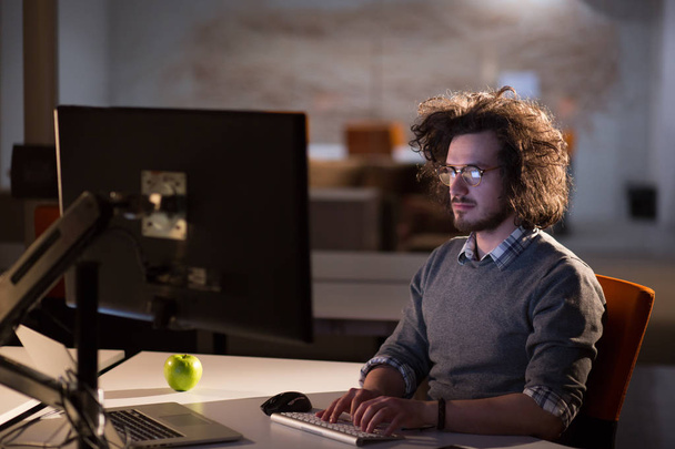 man working on computer in dark office - Foto, Imagen