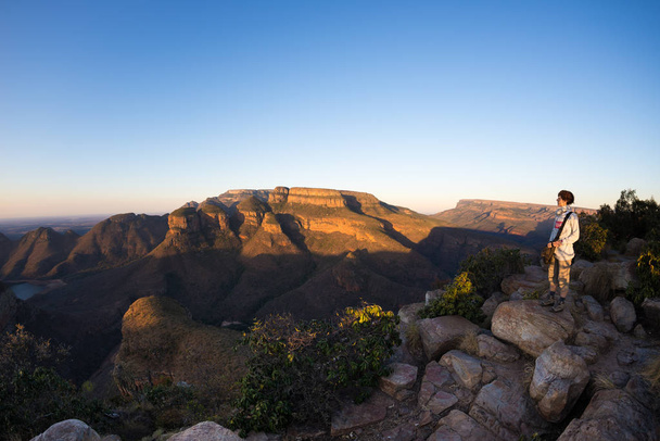 Blyde River Canyon, cíl cesty v Jižní Africe. Turista při pohledu na panorama. Poslední slunce na horských hřebenech. Fisheye zkreslený pohled shora. - Fotografie, Obrázek