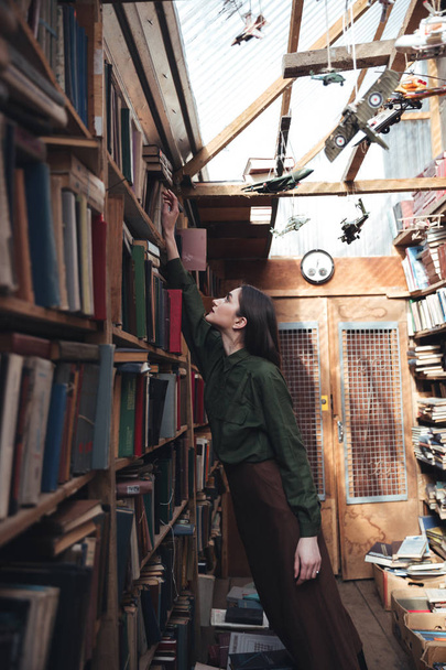 Side view of woman taking book from shelf - 写真・画像