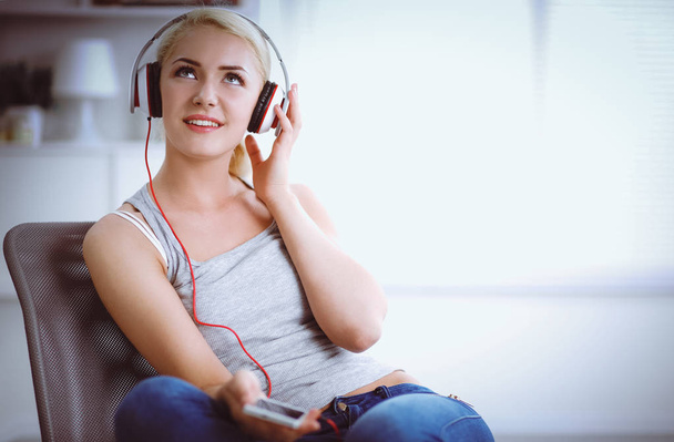 Young beautiful woman at home sitting on sofa and listening music - Foto, imagen