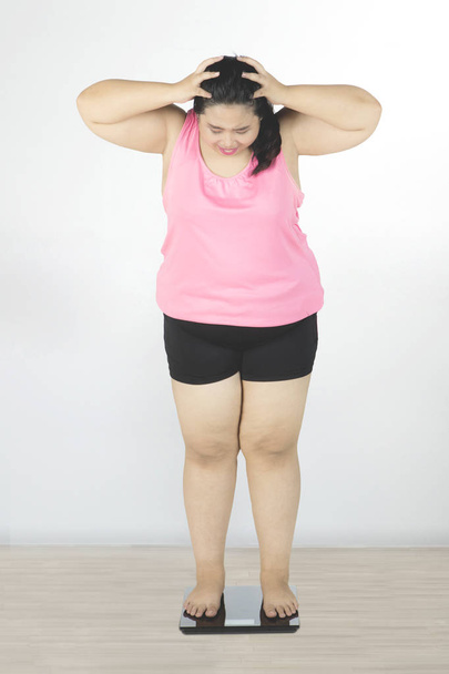 Obese woman looking weight scale  - Foto, imagen