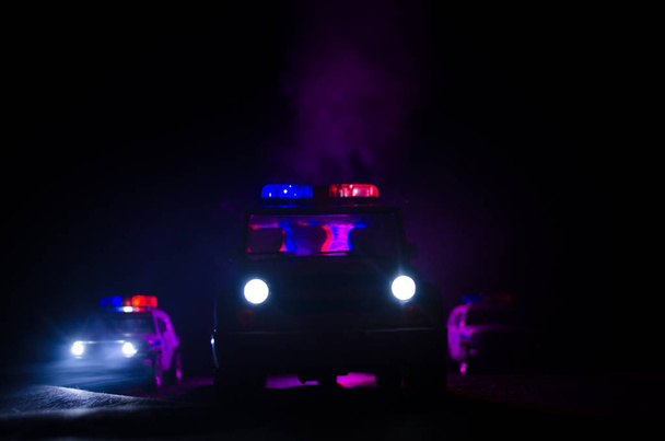 Geschwindigkeitsbeleuchtung von Polizeiwagen in der Nacht auf der Straße. Polizeiautos im Nebel unterwegs. Selektiver Fokus. Verfolgungsjagd - Foto, Bild