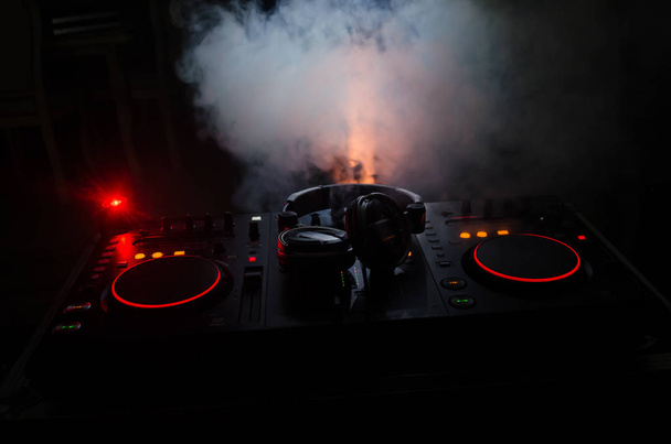 DJ κλώση, ανάμειξη και ξύσιμο σε ένα νυχτερινό κλαμπ, τα χέρια του dj τσίμπημα διάφορα στοιχεία ελέγχου γραμμής στο κατάστρωμα του dj, φώτα strobe και την ομίχλη, επιλεκτική εστίαση - Φωτογραφία, εικόνα