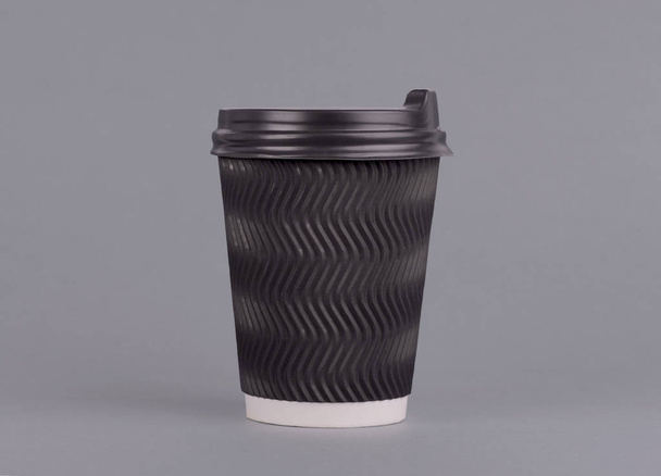 Kaffeetasse aus schwarzem Papier vorhanden. auf grauem Hintergrund. Kaffeeattrappe zum Mitnehmen - Foto, Bild