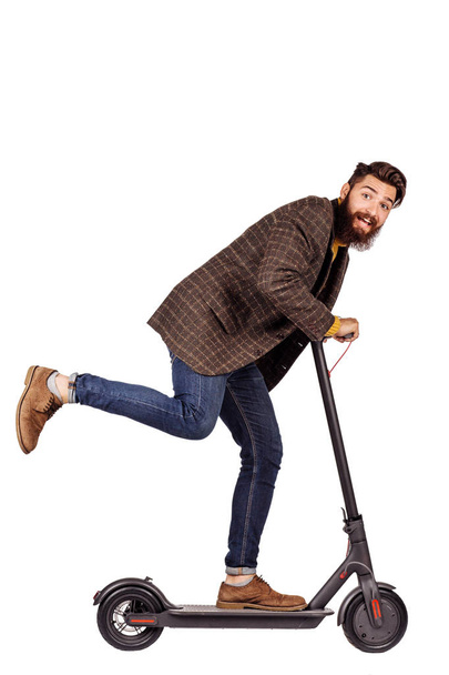 bearded man holding the electric scooter and riding it while feeling delighted. image on white background - Fotó, kép