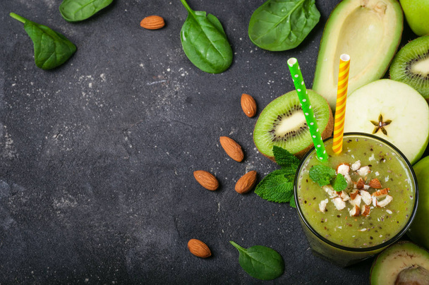 Smoothie verde saludable e ingredientes sobre fondo oscuro. Batido kiwi con frutas y almendras. Superalimentos, dieta, desintoxicación, salud, comida vegetariana
 - Foto, imagen